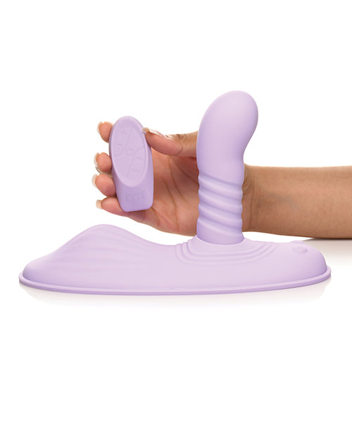 A hand holds the wireless remote next to the Inmi Thrust N' Grind. The remote is oval-shaped with a flat base. | Kinkly Shop