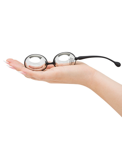 A palm is held out flat. The Inner Goddess Jiggle Balls rests in their hand. The balls are oval-shaped and look long with an average-penis thickness. | Kinkly Shop