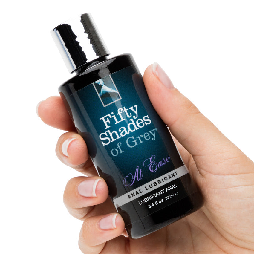 A hand holds the Fifty Shades of Grey at Ease bottle. It's a cylindrical bottle that looks comfortable to grip without being too thick. | Kinkly Shop