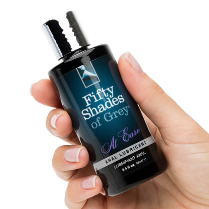 A hand holds the Fifty Shades of Grey at Ease bottle. It's a cylindrical bottle that looks comfortable to grip without being too thick. | Kinkly Shop