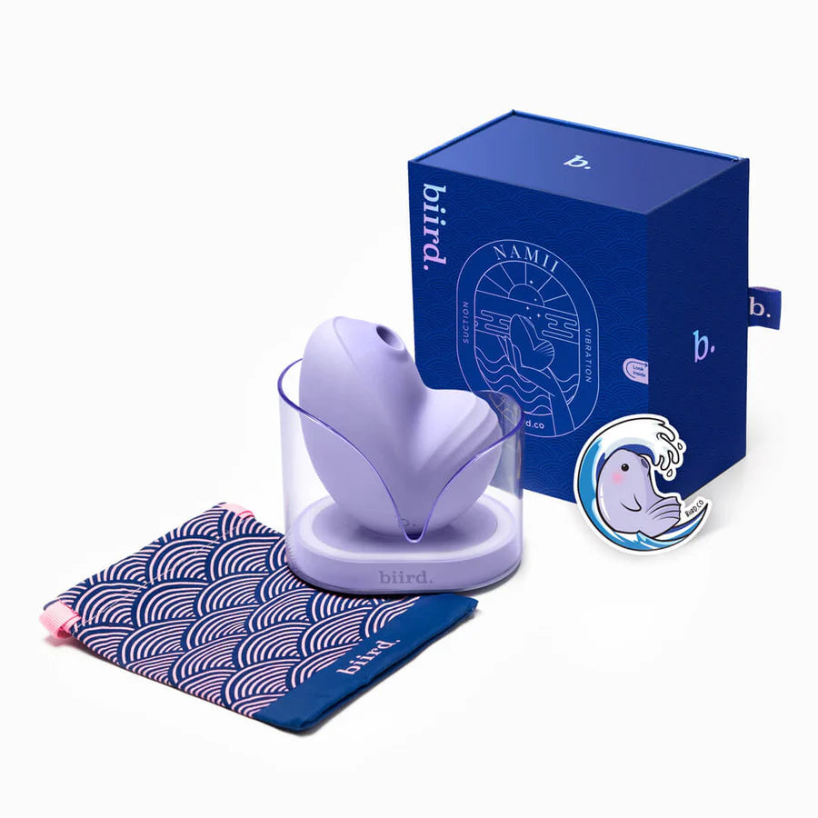 The Biird Namii in Lilac shown with everything it comes with. It comes with a drawstring storage bag, the vibrator, the charging cable, and the charging base, and a sticker. | Kinkly Shop