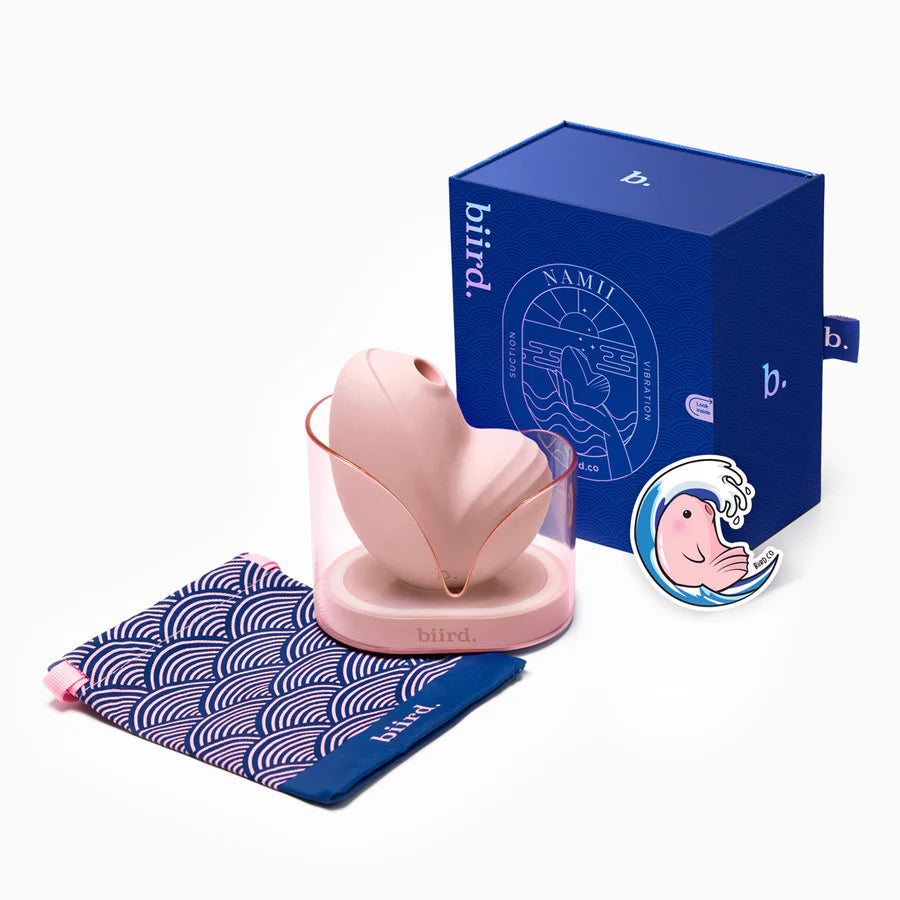 The Biird Namii in Peach shown with everything it comes with. It comes with a drawstring storage bag, the vibrator, the charging cable, and the charging base, and a sticker. | Kinkly Shop