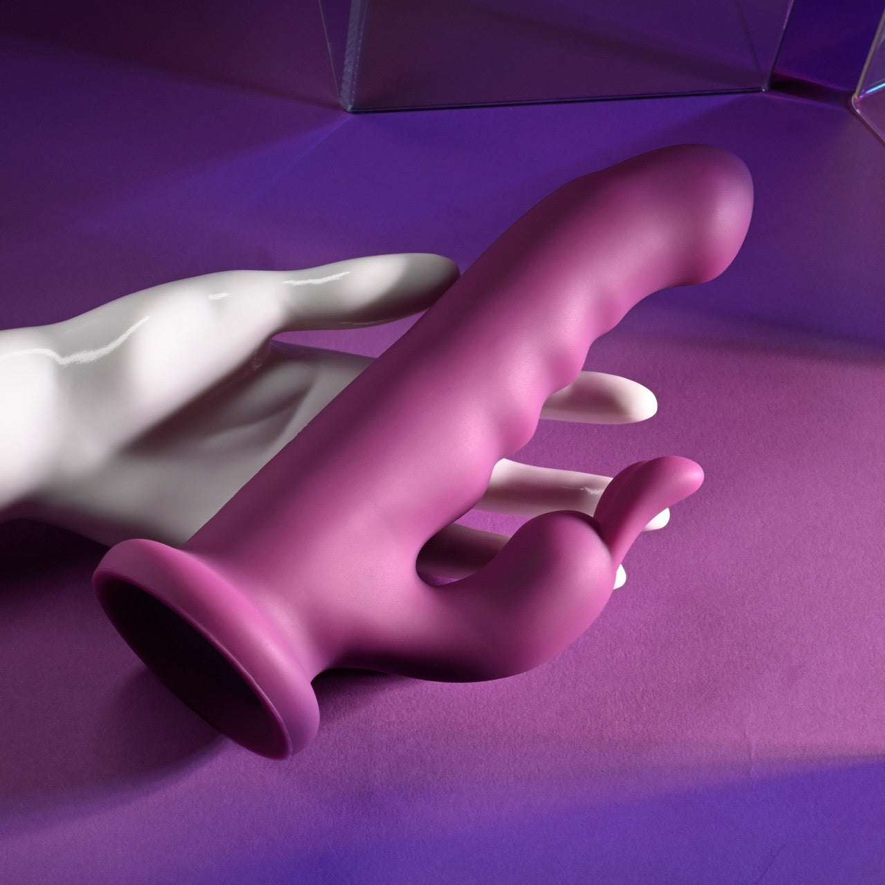 A mannequin hand holds the Playboy Fluffle. The insertable shaft has a ribbed texture on it with a slightly curved tip. There are bunny ears on the clitoral attachment. | Kinkly Shop