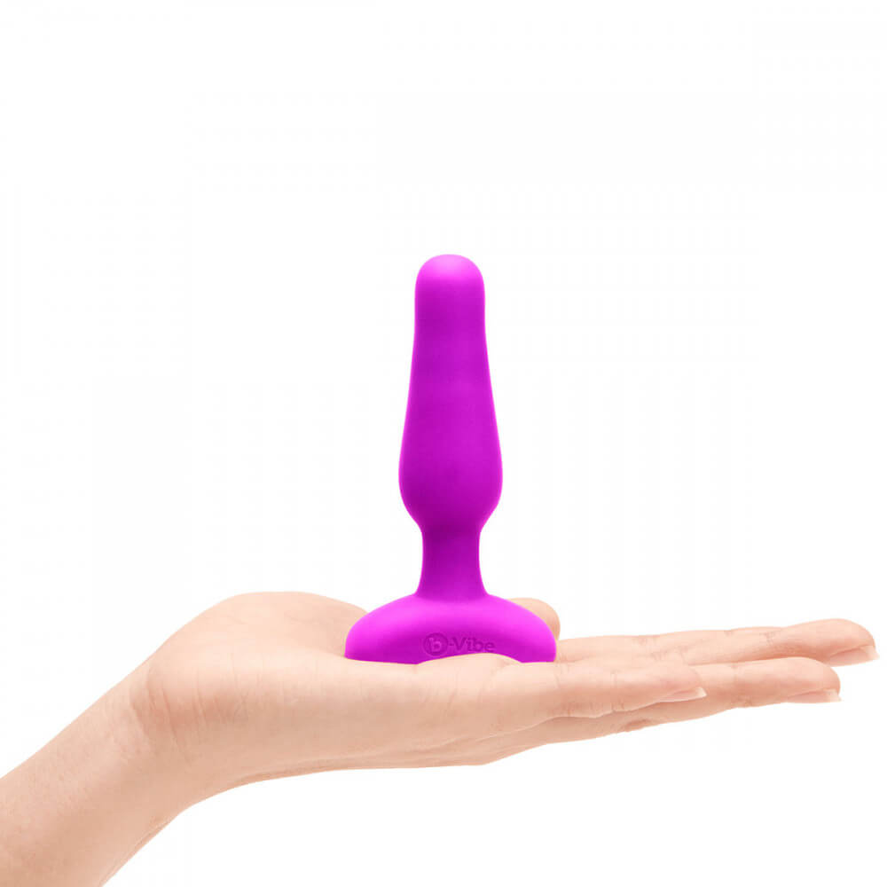 A palm lays flat. On top of the palm is the b-Vibe Remote Novice Plug. It looks slender and short compared to the hand. | Kinkly Shop