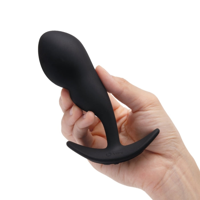 A hand holds the B-Vibe Remote Control P-Spot Snug Plug in Black. This is the thicker and the heavier of the two plugs. | Kinkly Shop
