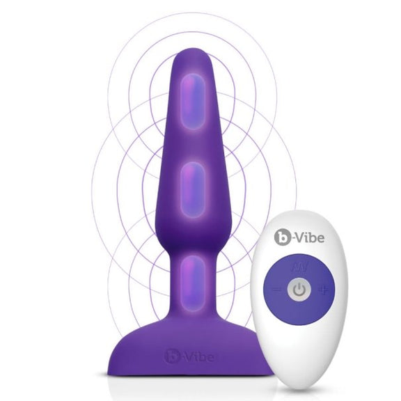 b-Vibe Remote Trio Plug in Purple against a white background. An overlayed illustration showcases where the three different motors are located on the length of the plug. One is in the tip, one is at the base of the inserted portion, and one is in the retention area of the plug. | Kinkly Shop