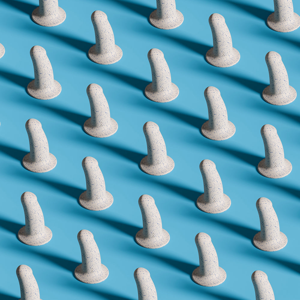 An entire army of Biird Boo sitting upright on an orange background. A strong light source from the lower right corner of the image is causing each one of the dildos to cast a very long shadow across the orange background. It's very artsy. | Kinkly Shop