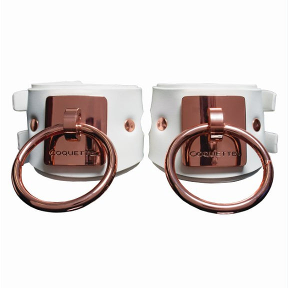 Coquette White and Rose Gold Adjustable Cuffs in front of a white background. The white leather is a snow white leather color while the Rose Gold metal color is darker in nature. The O-rings are very large, designed to be a focal point of the cuffs. | Kinkly Shop