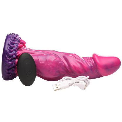 The Creature Cocks Xenox Vibrating Remote-Controlled Dildo on its side, shown with everything it comes with. It's sitting next to the remote control and the charging cable. | Kinkly Shop