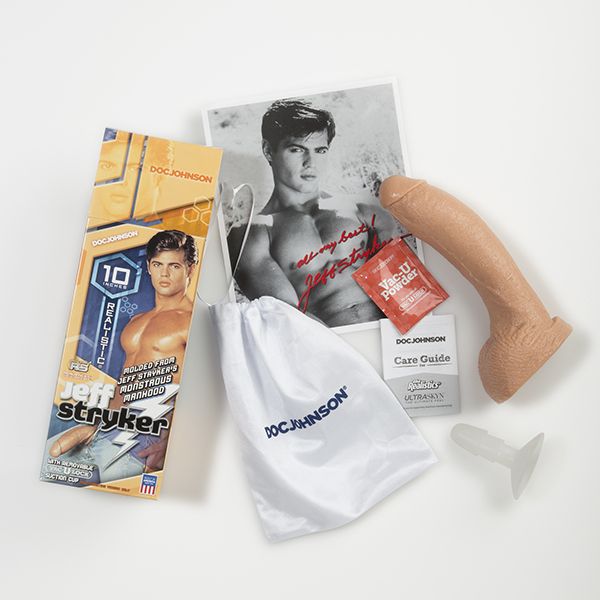 The Signature Cocks - Jeff Stryker Firmskyn dildo shown next to everything that comes with it. It includes a drawstring storage bag, a care guide, Vac-u-Lock powder, a picture of Jeff Stryker, and the Vac-U-Lock suction cup attachment base. | Kinkly Shop