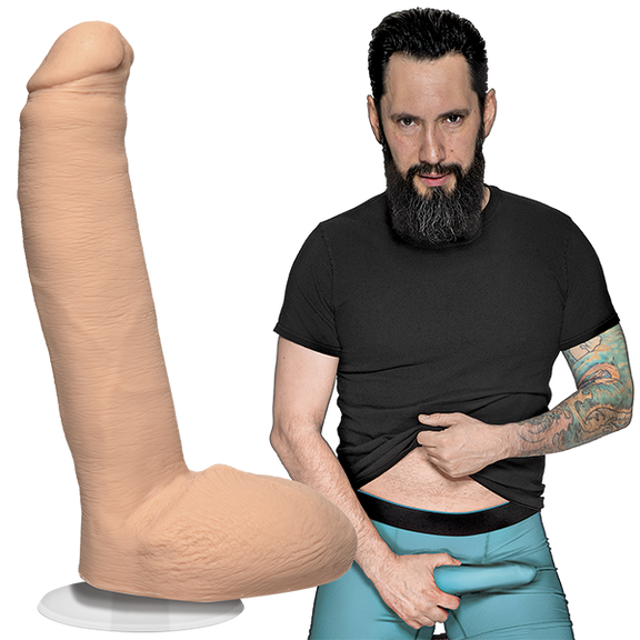 Tommy Pistol is looking into the camera while holding his erection that's in his boxer briefs. The Signature Cocks - Tommy Pistol dildo is shown next to the porn star, lifecast and modeled directly from him. | Kinkly Shop