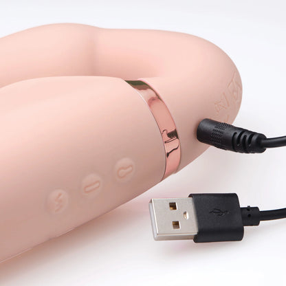 Close-up of the charging cable plugged into the Strap U Ergo-Fit Inflatable & Vibrating Strapless Strap-On. It's a pin-style charger that must penetrate the toy. There are also 3 buttons to control the toy's functions right next to the charging port. | Kinkly Shop