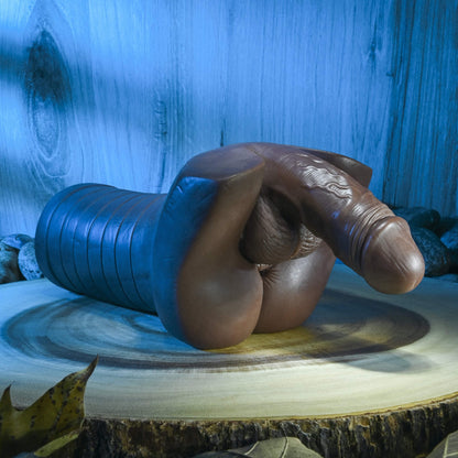 The Evolved Backdoor Bash resting "upside down". The penis of the stroker is pointing downwards, with gravity, showcasing the slightly flexible design of the material of the penis to mimic an erection. | Kinkly Shop