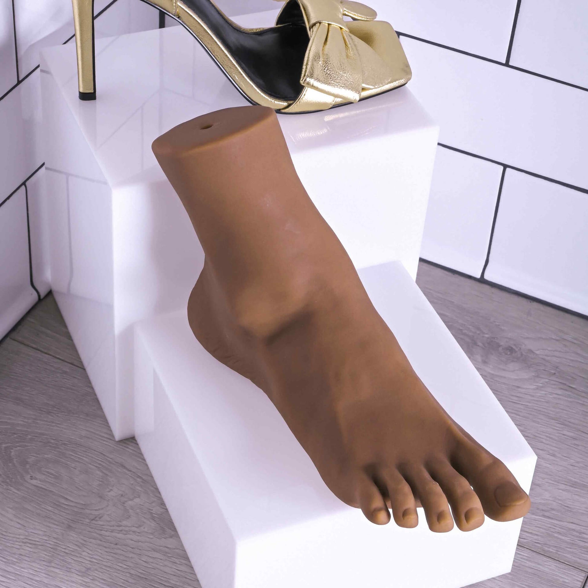 The Evolved Pussy Footin' sitting on a riser. The "skin" of the stroker looks very smooth. It even has indentations near the "ankle" for realism. Distinct toe nails are also etched into the stroker material on the toes. | Kinkly Shop