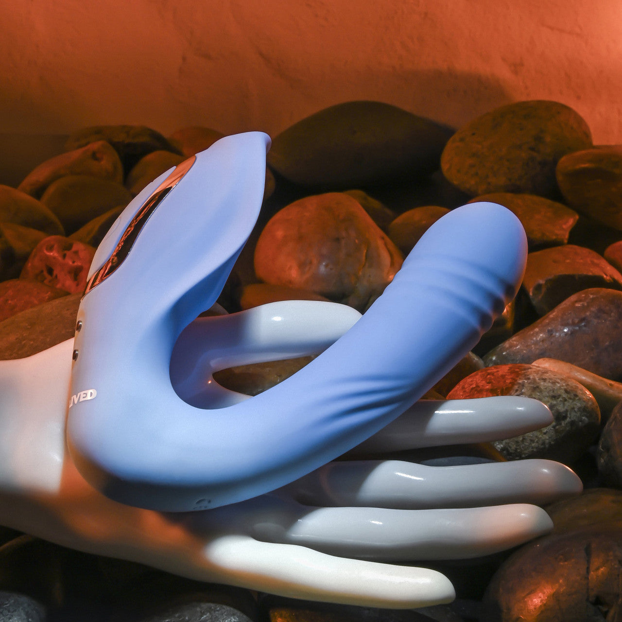 The Evolved Tap & Thrust rests on top of a mannequin hand. The vibrator's insertable length is about as thick as three fingers with a V-like design that takes up most of the mannequin's palm space. | Kinkly Shop