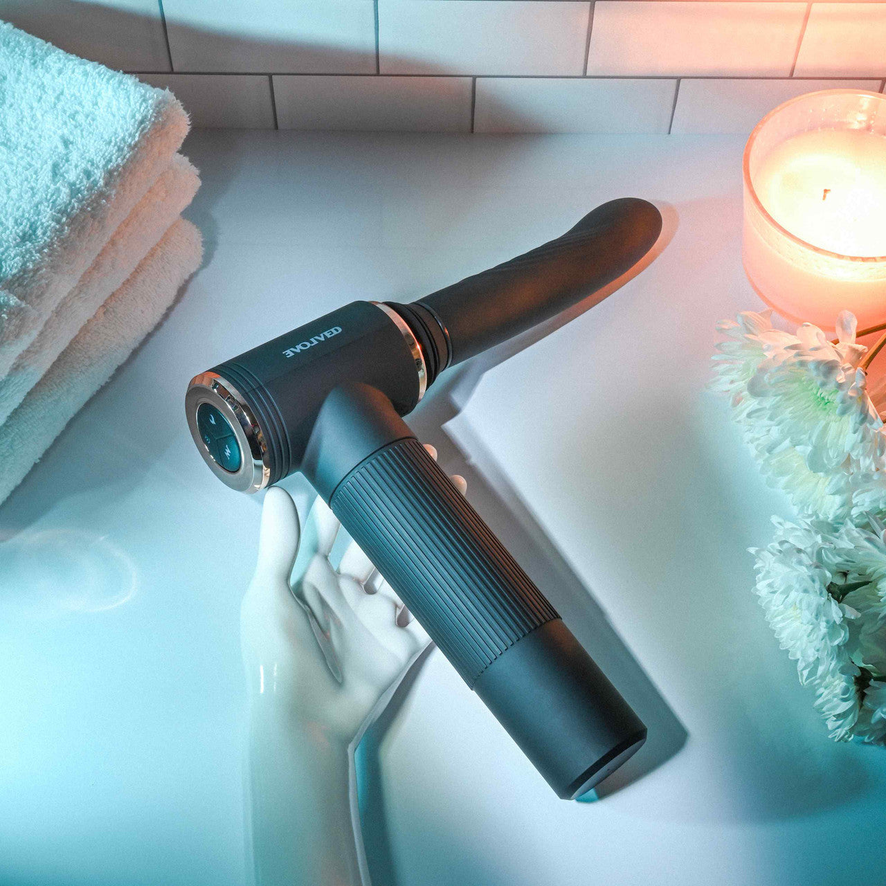 The Evolved Too Hot to Handle Thrusting Machine lays out on a countertop. A mannequin handle is gripping at the handle, showcasing how the thrusting machine can be handheld. | Kinkly Shop