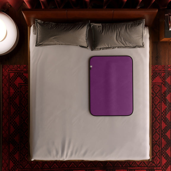 The Liberator Waterproof Fascinator Throw Mini laid out on top of a nicely-made bed. | Kinkly Shop