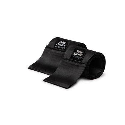 A close-up of the two black satin restraint ties with the Fifty Shades of Grey branding tags on them. | Kinkly Shop