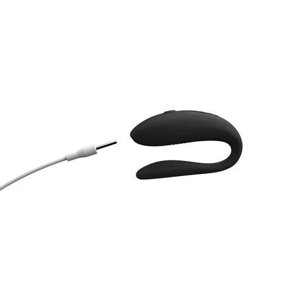 A close-up showcases the charging cable about to plug into the tip of the We-Vibe Sync Lite. It plugs into the tip of the toy near the clitoral end. | Kinkly Shop