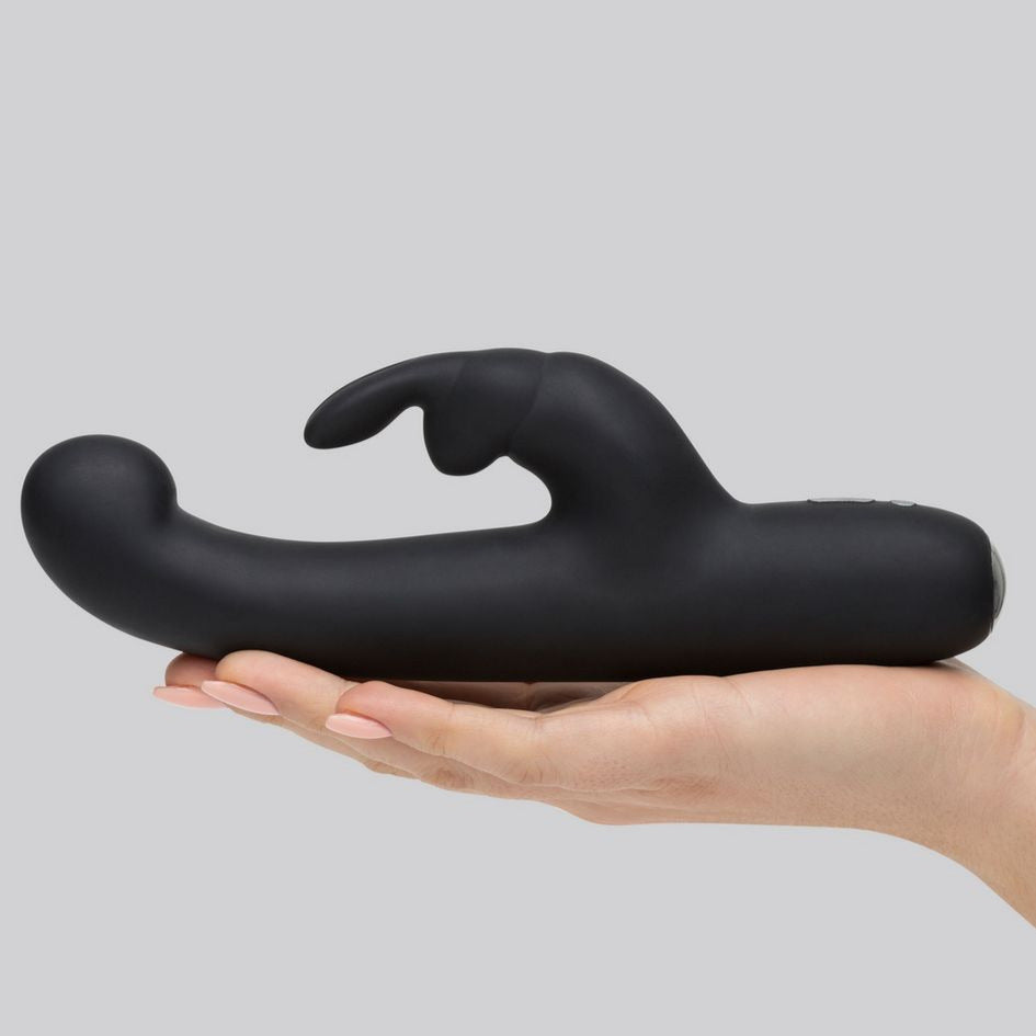 A hand is laid out flat. The Happy Rabbit Slimline G-spot is in their hand, extending much longer than the person's outstretched hand. The toy looks formidable in length from this view. | Kinkly Shop