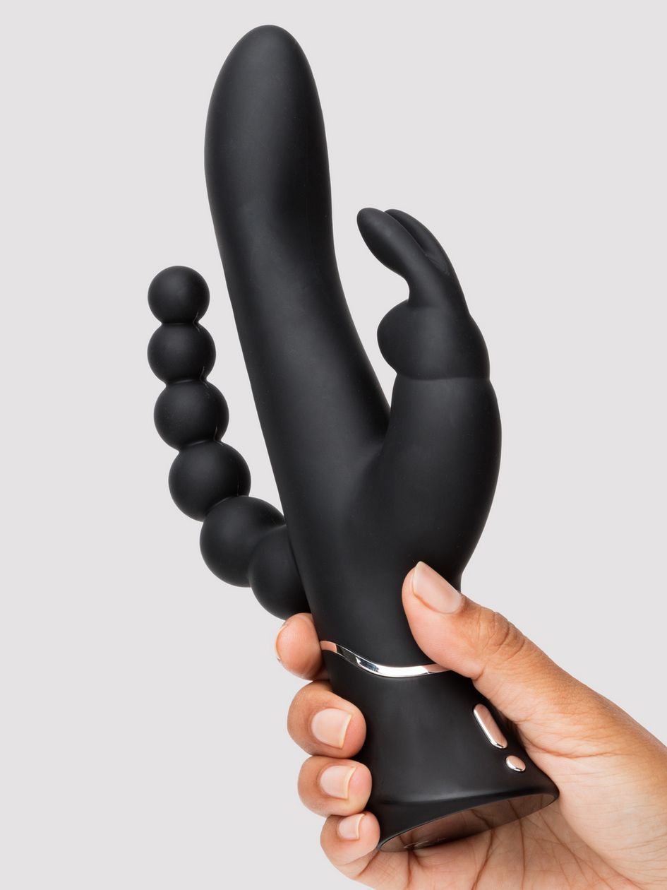 A hand holds the Happy Rabbit Triple Curve. It looks very formidable with a lot of ways to experience pleasure right at the palm of their hand. | Kinkly Shop