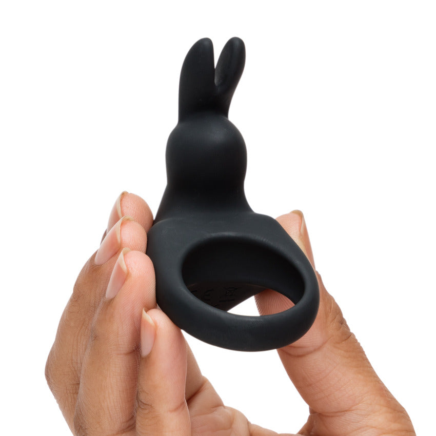 A hand holds the Happy Rabbit Rechargeable Cock Ring, showcasing the small size. The extended rabbit ear prong looks like it extends most of the length of a person's finger. | Kinkly Shop