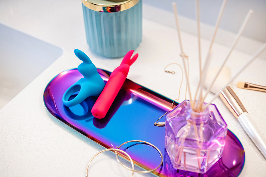 The Happy Rabbit Rechargeable Cock Ring shown on a make-up tray. The vibrator is about as big as hoop earrings. | Kinkly Shop