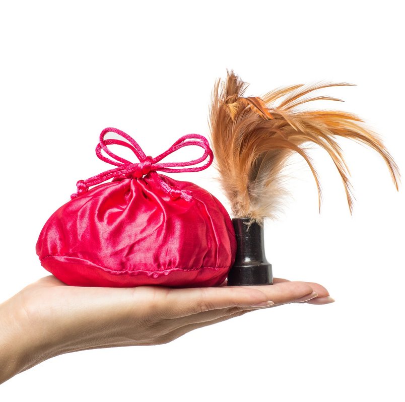Bag of Kama Sutra Honey Dust Body Powder shown in its drawstring pouch. The feather, with its easy-handle handle, is shown next to the drawstring pouch. | Kinkly Shop