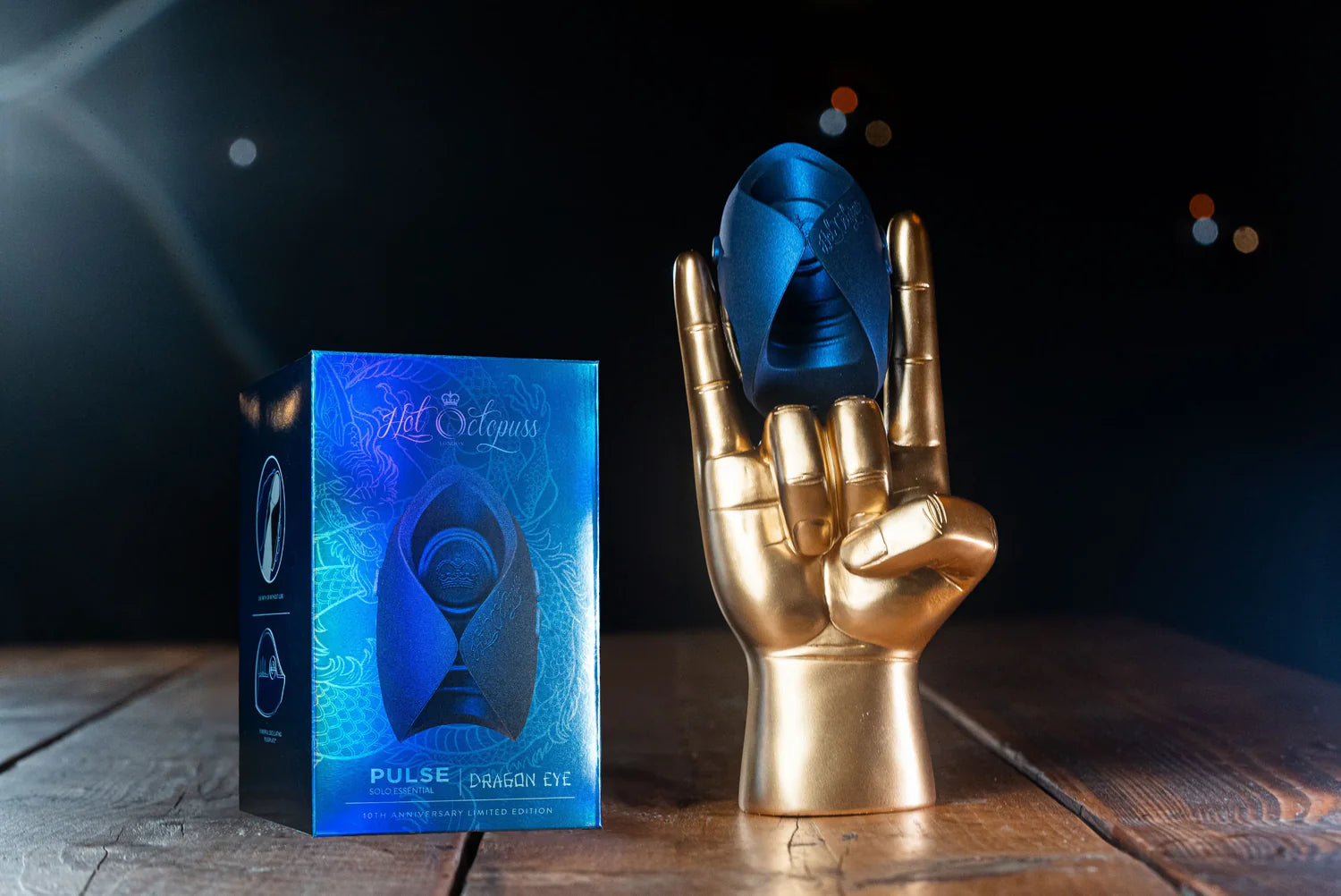 The Hot Octopuss Pulse Solo Essential - Limited Edition held up by a golden mannequin hand. The stroker is about as wide as three fingers in width. | Kinkly Shop