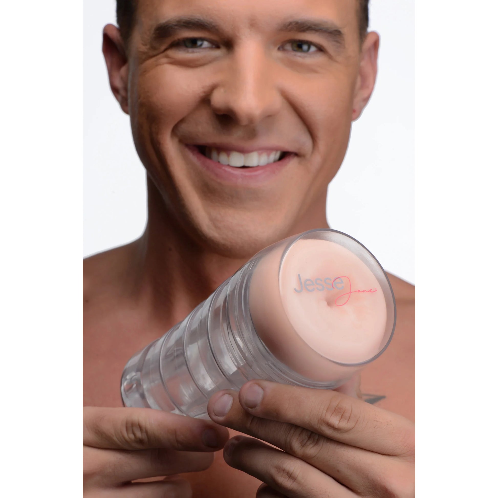 A person is smiling and looking into the camera. They are holding the Jesse Jane Deluxe Signature Ass Stroker, with the lid on the case, showcasing how easily grippable in one hand the stroker looks. | Kinkly Shop