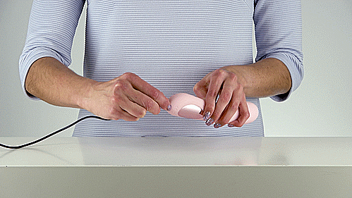 GIF shows a person holding the KIIROO Pearl3 G-Spot Vibrator with both hands. They take the charging cable for the Pearl 3 and plug it into the base of the vibrator, showing how the charging cable plugs in to charge. | Kinkly Shop