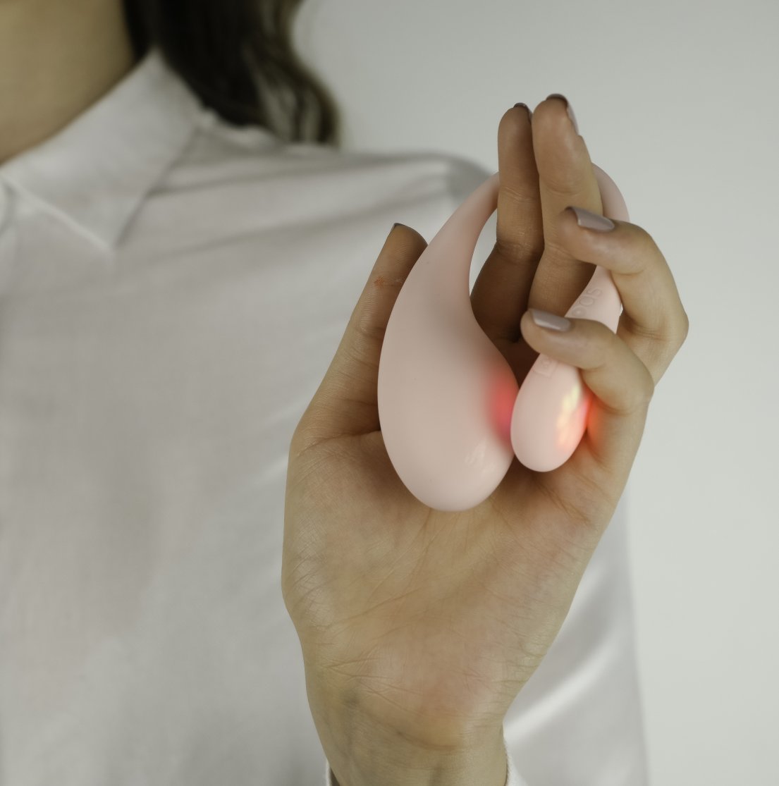 A person holds the KIIROO Spot in their hands. The LED lights on the tail of the Spot give off a gentle red glow against the toy's body and the person's fingers. | Kinkly Shop