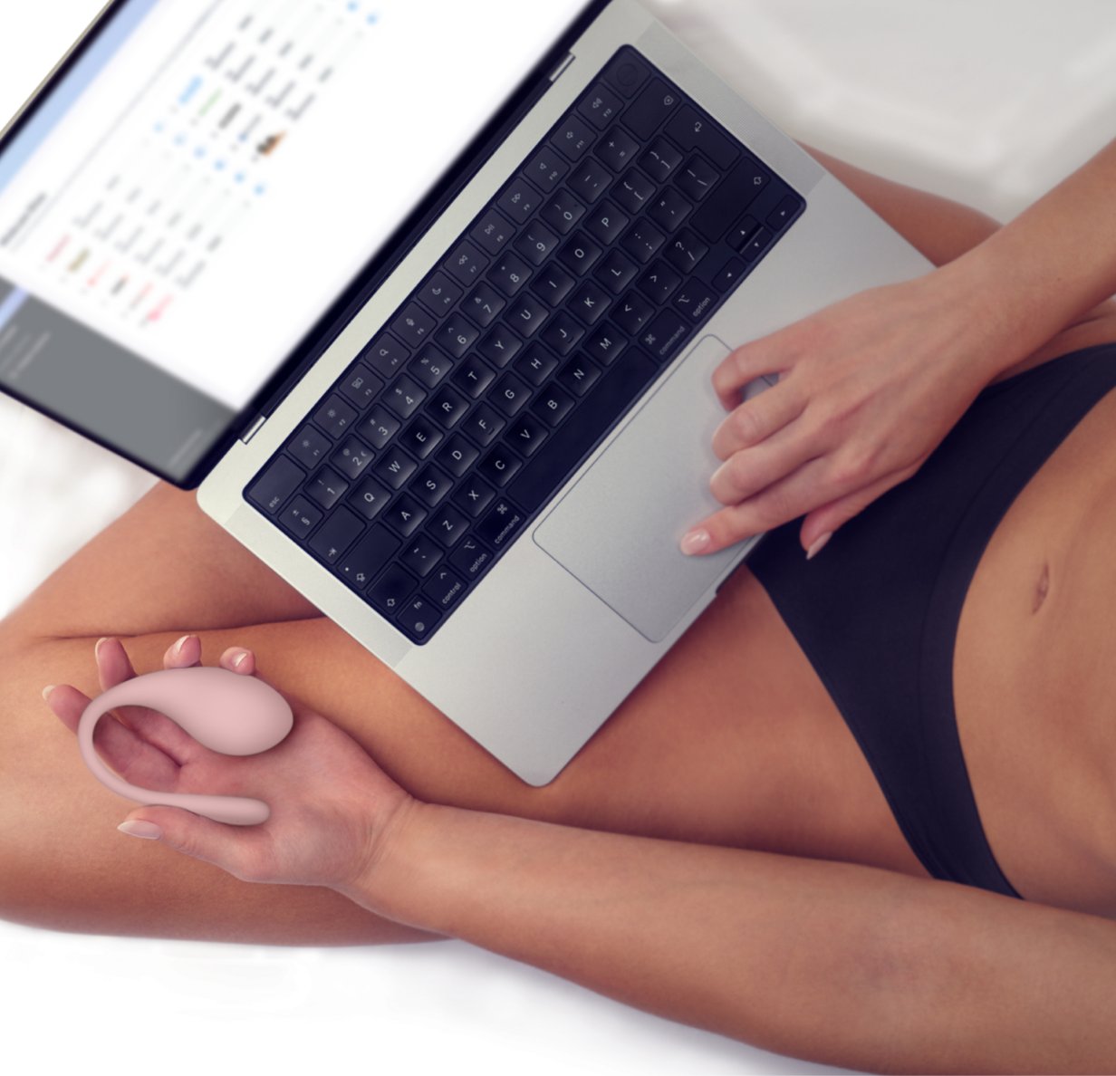 A person has a lap sitting on their lap and is holding the KIIROO Spot in their palm. The vibrator is smaller than their palm, but it looks like it would peek out if the person enclosed their full hand around the toy. | Kinkly Shop
