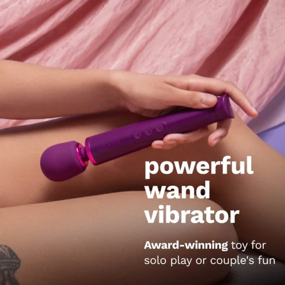 A person holds the Le Wand Petite Rechargeable between their thighs. The wand looks particularly lightweight in their hand. Text on the image reads: Powerful wand vibrator. Award-winning toy for solo play or couple's fun. | Kinkly Shop