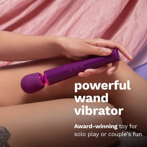 A person holds the Le Wand Petite Rechargeable between their thighs. The wand looks particularly lightweight in their hand. Text on the image reads: Powerful wand vibrator. Award-winning toy for solo play or couple's fun. | Kinkly Shop