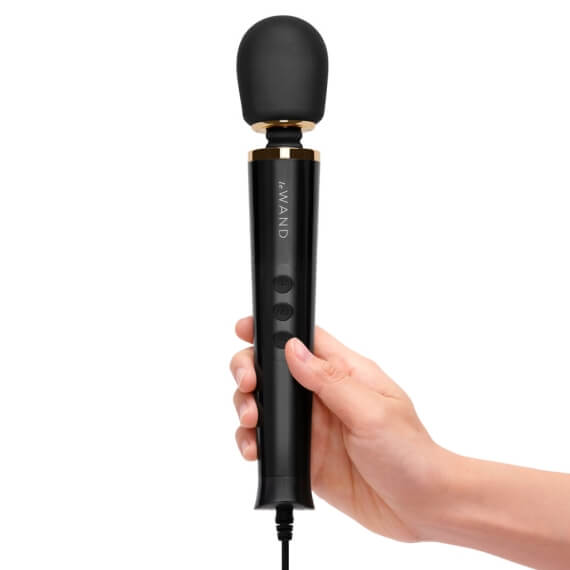 A hand holds the Le Wand Petite Plug-In Massager. The hand's width takes up about 1/2 of the space along the length of the Le Wand Petite Plug-In Massager. Their thumb naturally rests near the three buttons that control the vibrations. | Kinkly Shop