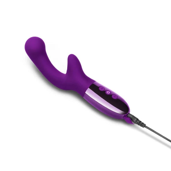 The Le Wand XO plugged into a charger. The charging cable plugs into the base of the handle where the splashproof charging port cover is opened. | Kinkly Shop