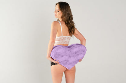 A person holds the Liberator Heart Wedge in Faux Fur behind their body, next to the butt. The Wedge looks wider than their small body | Kinkly