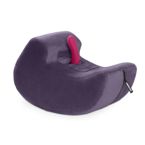 The Liberator Pulse in Purple up against a plain white background. A pink vibrator is protruding from the center of the shape at an angle that would make it easy to ride or grind against. The Pulse has a shape like a sideways comma with a rocking base that allows the shape to rock backwards and forwards with ease. | Kinkly Shop