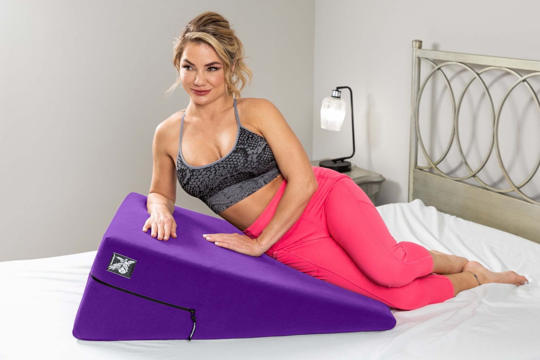A person in athletic clothing is laying on their side on top of the Liberator Ramp. The Ramp is very long, and it is just as long as the person's shoulder all the way down to their knees. Despite placing all of their body weight on the Ramp, the Ramp shows minimal signs of compression, and it almost looks like the person's hips are simply laying on top of a flat table. The Ramp is much wider than the person, looking like two people could spoon on top if they were both this person's size.