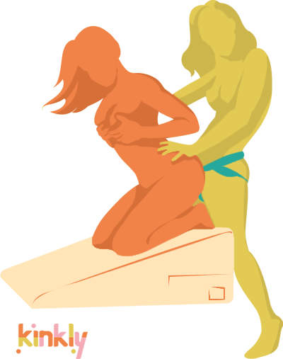 Illustration shows the Liberator Ramp in use. The receiving partner is kneeling at the top of the Liberator Ramp. The penetrating partner stands with their thighs against the Ramp to penetrate their partner from behind. | Kinkly Shop