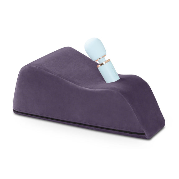The Liberator Wanda in Plum Purple up against a plain white background. There's a blue wand massager sitting in the Wanda is protruding upwards at an angle. | Kinkly Shop
