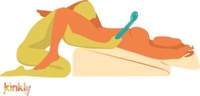 Illustration shows the Liberator Wedge and Liberator Ramp in use. The receiving partner is laying back on a Liberator Ramp with their hips on the tall end of the Ramp. They're using the Liberator Wedge as a pillow. The giving partner is providing oral to the receiving partner's hips in the air. | Kinkly Shop