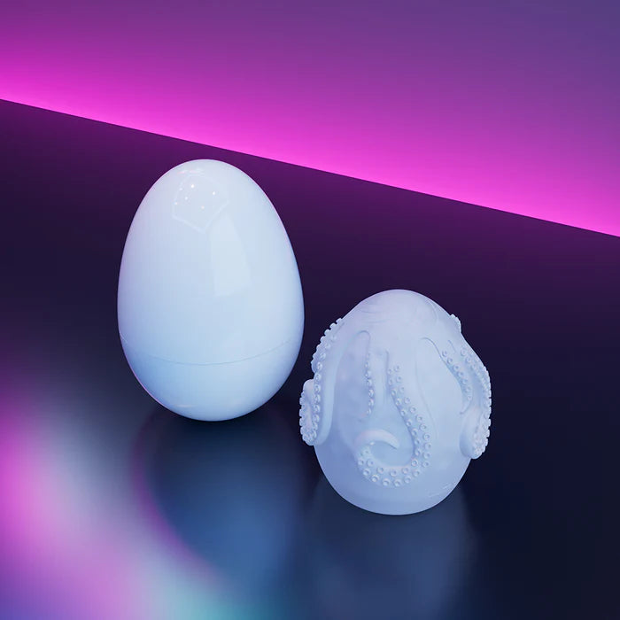 The Lovense Kraken interior TPE stroker sleeve shown sitting next to the plastic egg casing that it comes in. | Kinkly