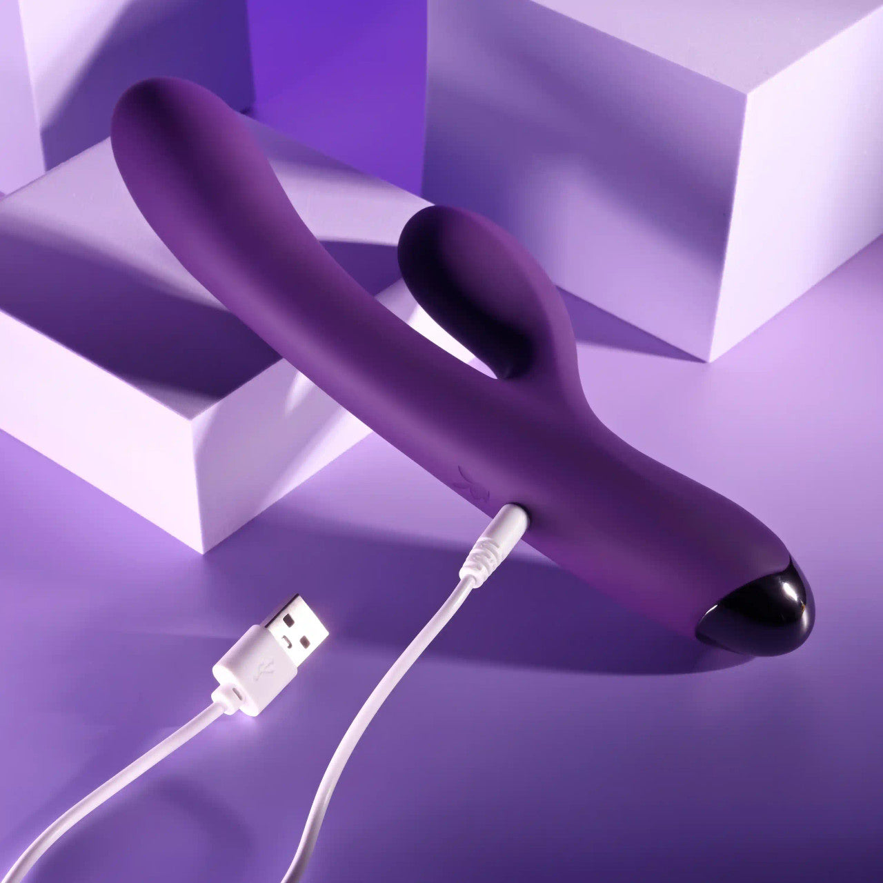 The Playboy New Crush is plugged into a charging cable. The charging cable plugs in on the lower third of the handle on the backside. | Kinkly Shop