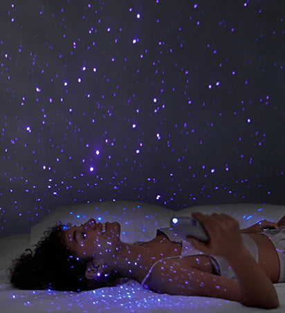 A person holds the Svakom Pulse Galaxie on their chest, allowing the vibrator to project a starry night projection onto the bedroom around them | Kinkly Shop