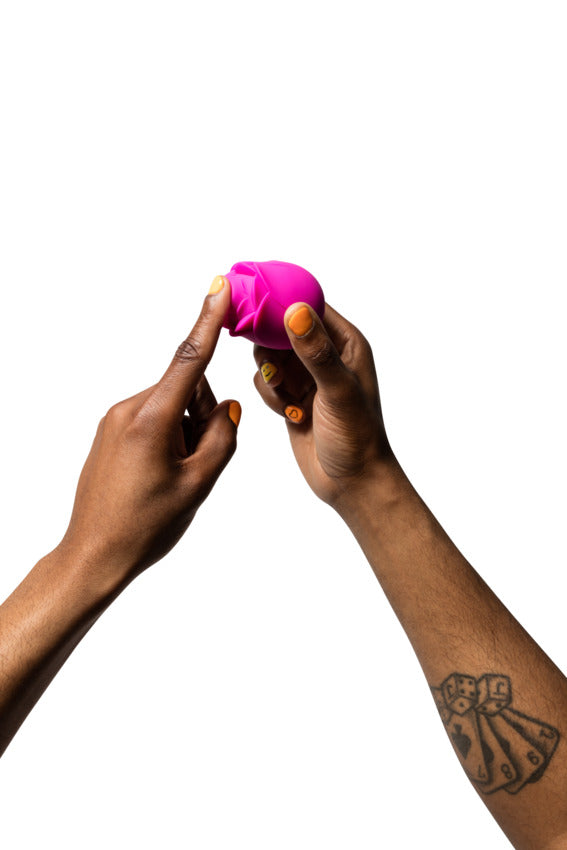Two hands hold the ROMP Rose. A person's single pointer finger is covering up the air suction vibrator tip. | Kinkly Shop