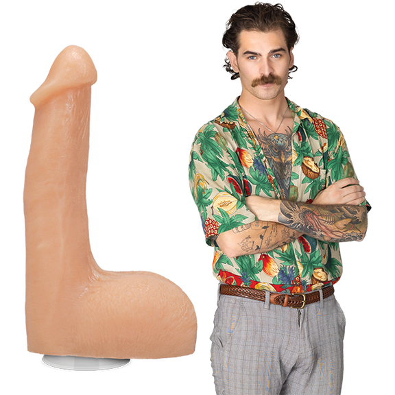 The Flesh Mechanic porn star stands fully clothed in 70's clothing with a bulge in their pants. The Signature Cocks - The Flesh Mechanic dildo is shown next to them, lifecast after their own shaft. | Kinkly Shop