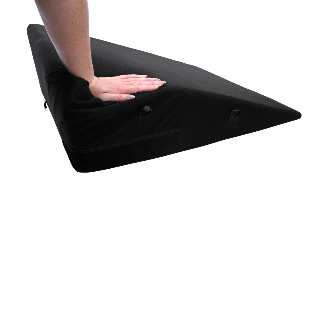 A hand pushes down the corner of the Sportsheets Positioner Plus. It compresses quite a bit under its weight. | Kinkly Shop