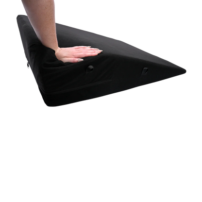 A hand pushes down the corner of the Sportsheets Positioner Plus. It compresses quite a bit under its weight. | Kinkly Shop